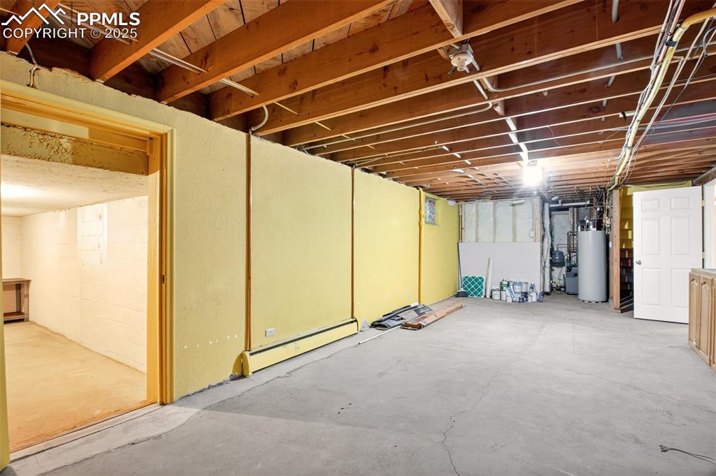 Image 31 of 43: Unfinished basement featuring a baseboard radiator and gas water heater