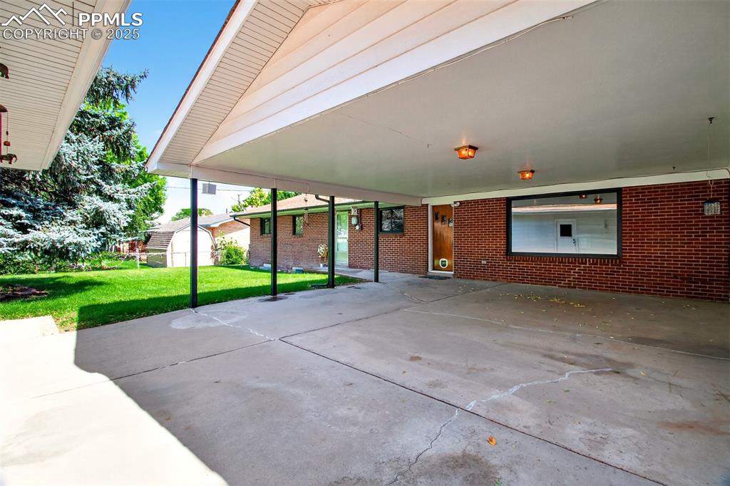 Image 35 of 43: View of patio with a storage unit and a carport