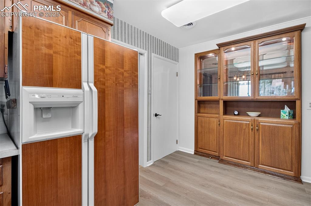 Image 4 of 43: Kitchen featuring white refrigerator with ice dispenser, brown cabinetry, l
