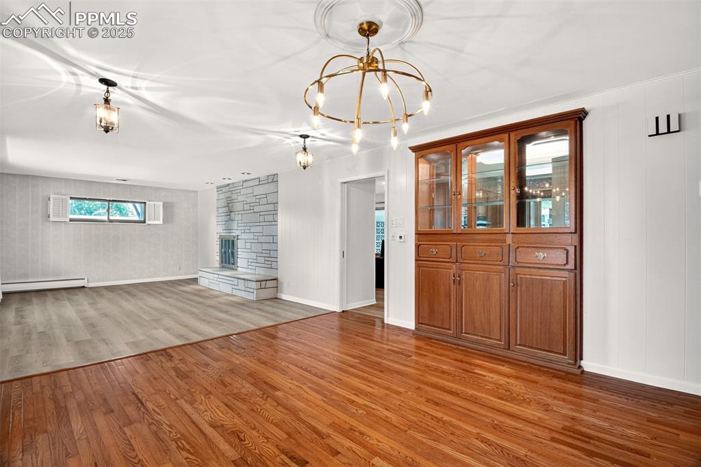 Image 8 of 43: Unfurnished living room featuring wood finished floors, a chandelier, a fir