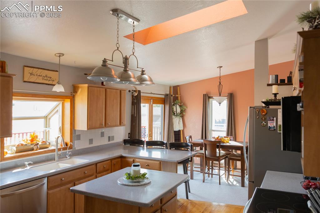 Image 16 of 49: Kitchen with appliances with stainless steel finishes, hanging light fixtur
