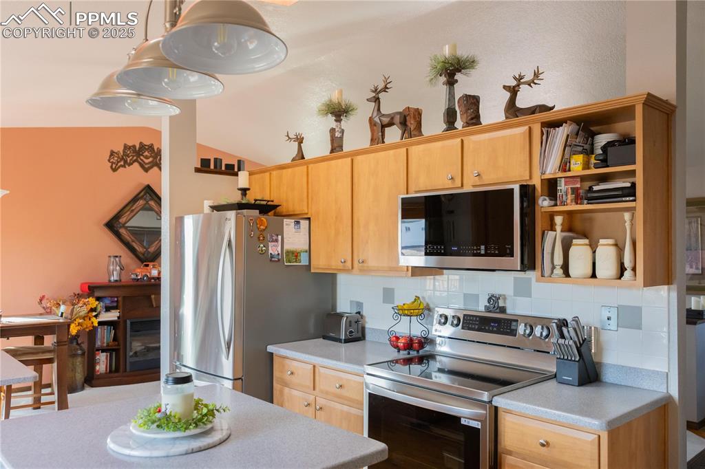 Image 18 of 49: Kitchen featuring stainless steel appliances, open shelves, decorative back