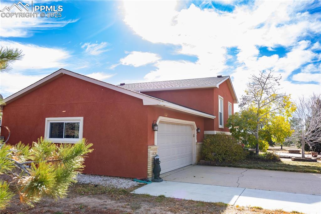 Image 3 of 49: View of property exterior featuring stucco siding, driveway, and a garage