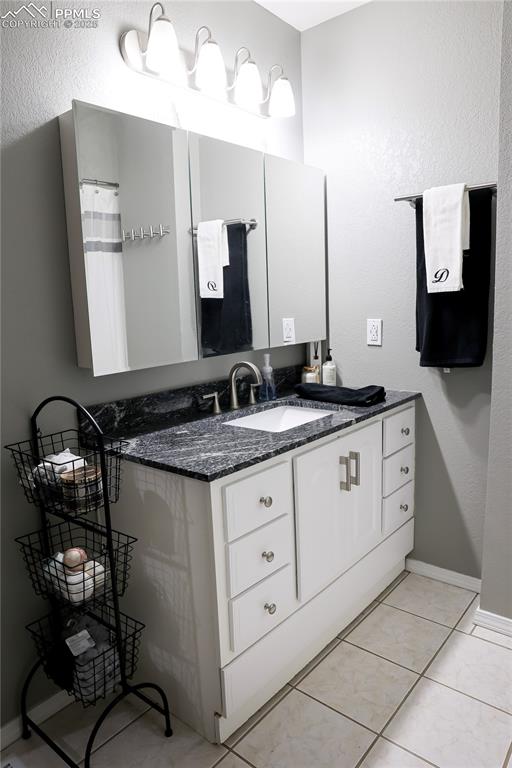 Image 39 of 49: Full bathroom featuring vanity, a textured wall, light tile patterned floor