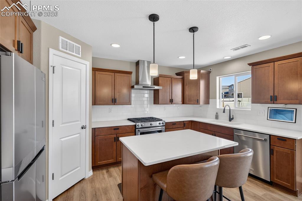 Image 12 of 38: Kitchen with stainless steel appliances, wood finish cabinetry, tasteful ba