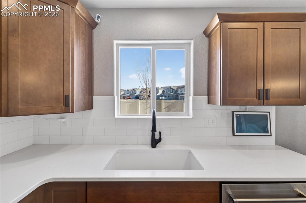 Image 13 of 38: Kitchen featuring light stone counters, stainless steel dishwasher, and woo