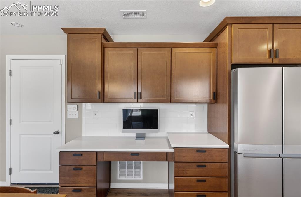 Image 14 of 38: Kitchen with freestanding refrigerator, wood finish cabinets, and tasteful 