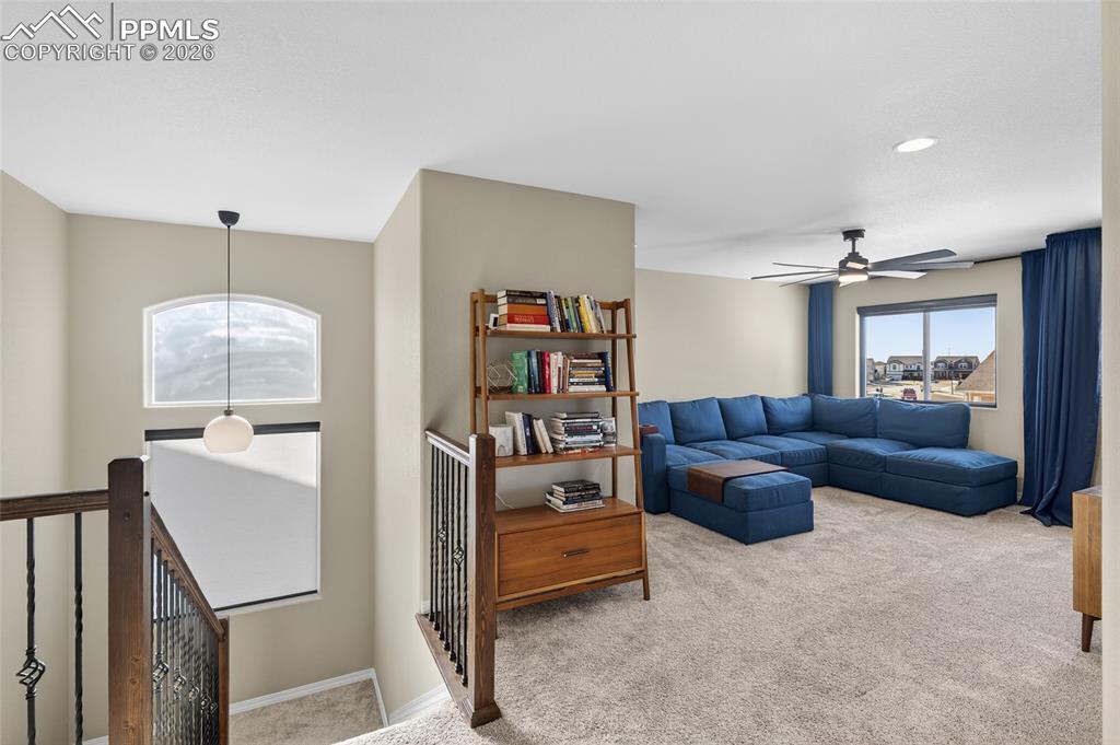Image 15 of 38: Living area with light colored carpet and ceiling fan