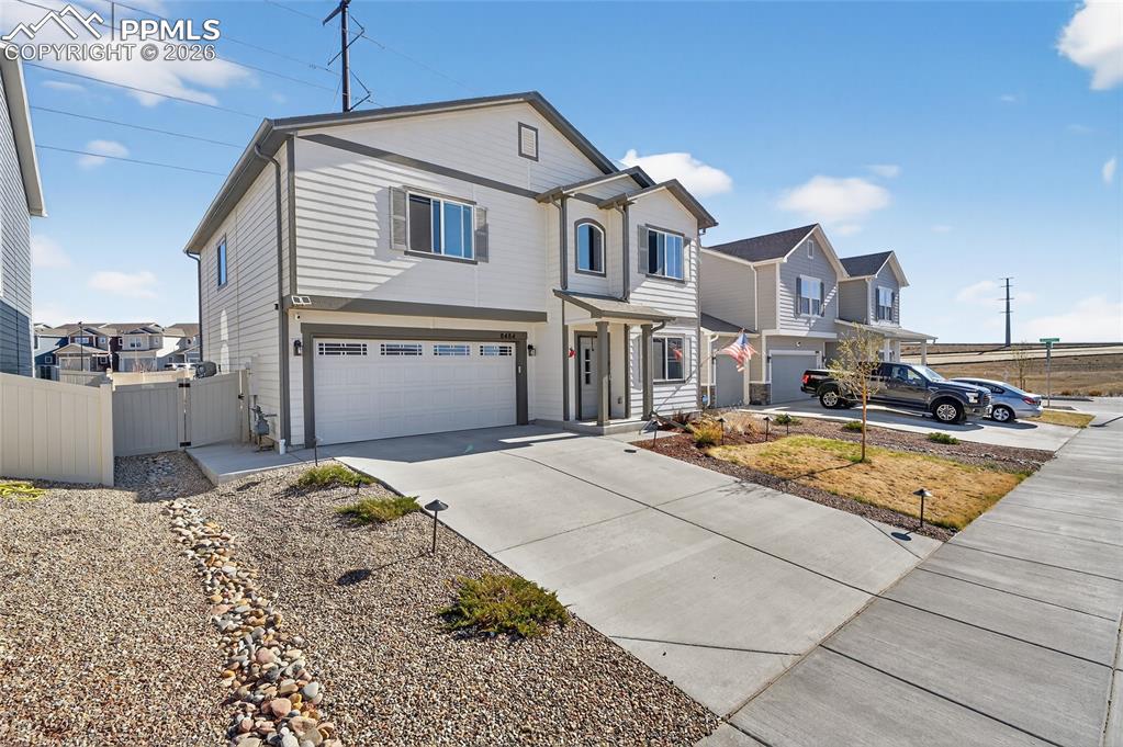 Image 2 of 38: Traditional-style house featuring a gate, driveway, a garage, and a residen