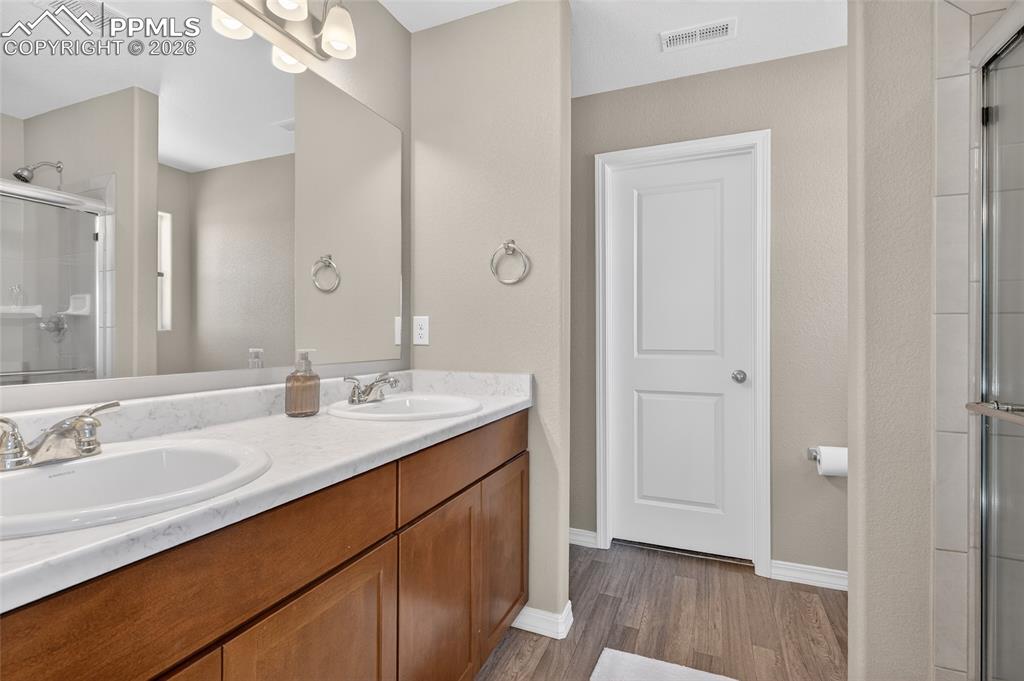 Image 20 of 38: Full bathroom featuring a stall shower, double vanity, and dark wood finish