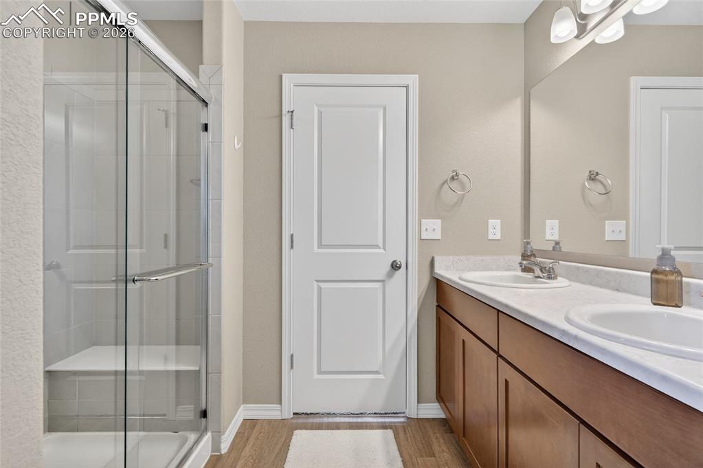 Image 22 of 38: Full bath with double vanity, a stall shower, and light wood finished floor