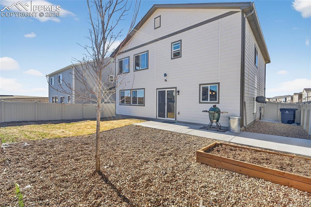 Image 34 of 38: Back of house with a patio, a fenced backyard, and a vegetable garden