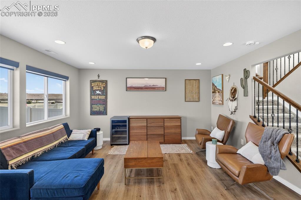 Image 6 of 38: Living room with wine cooler, wood finished floors, and recessed lighting