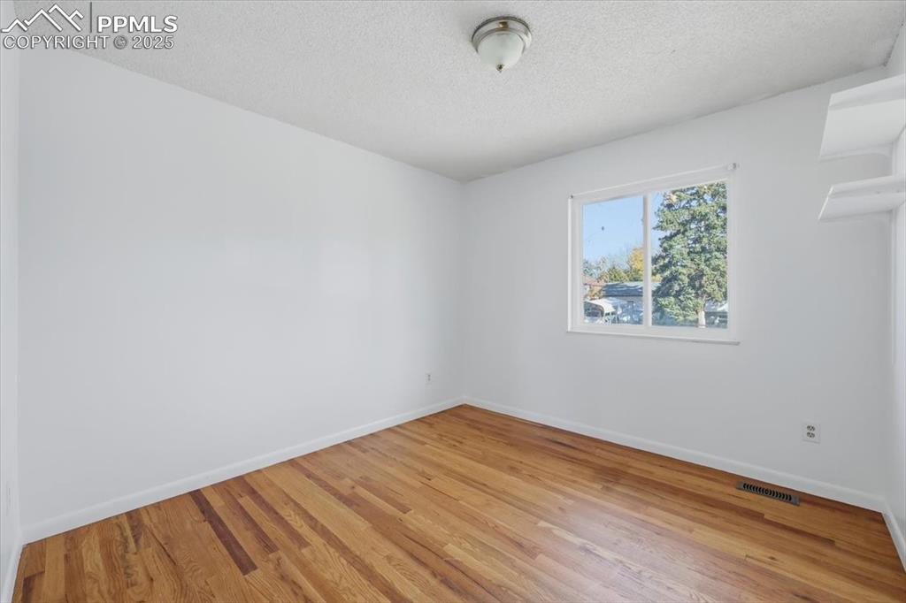 Image 11 of 26: Empty room with a textured ceiling and light wood finished floors