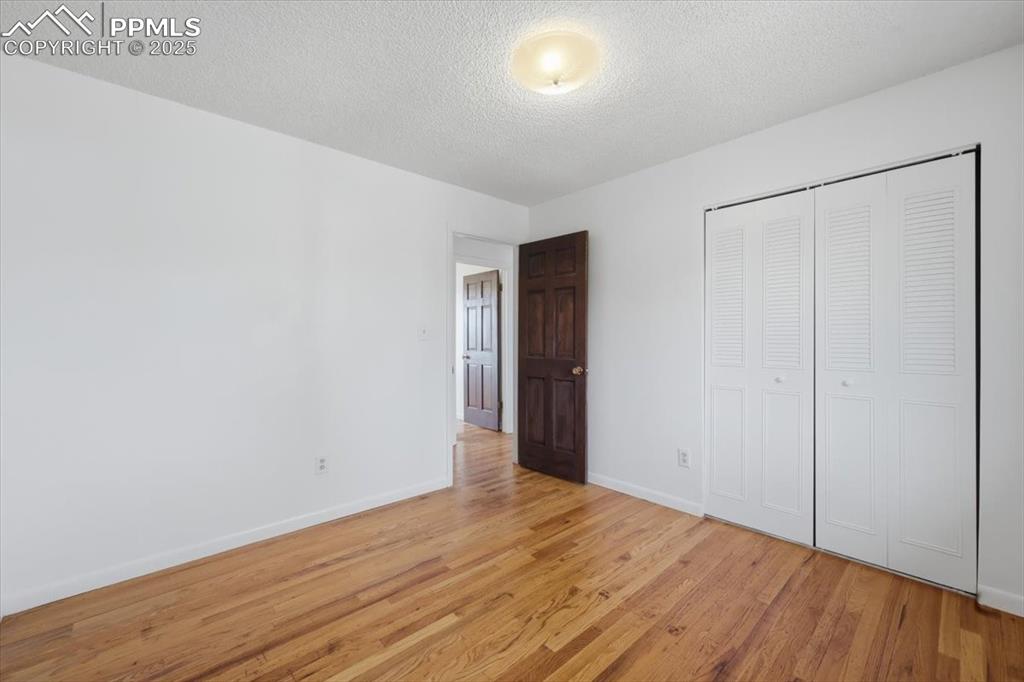 Image 12 of 26: Unfurnished bedroom with light wood-type flooring, a closet, and a textured
