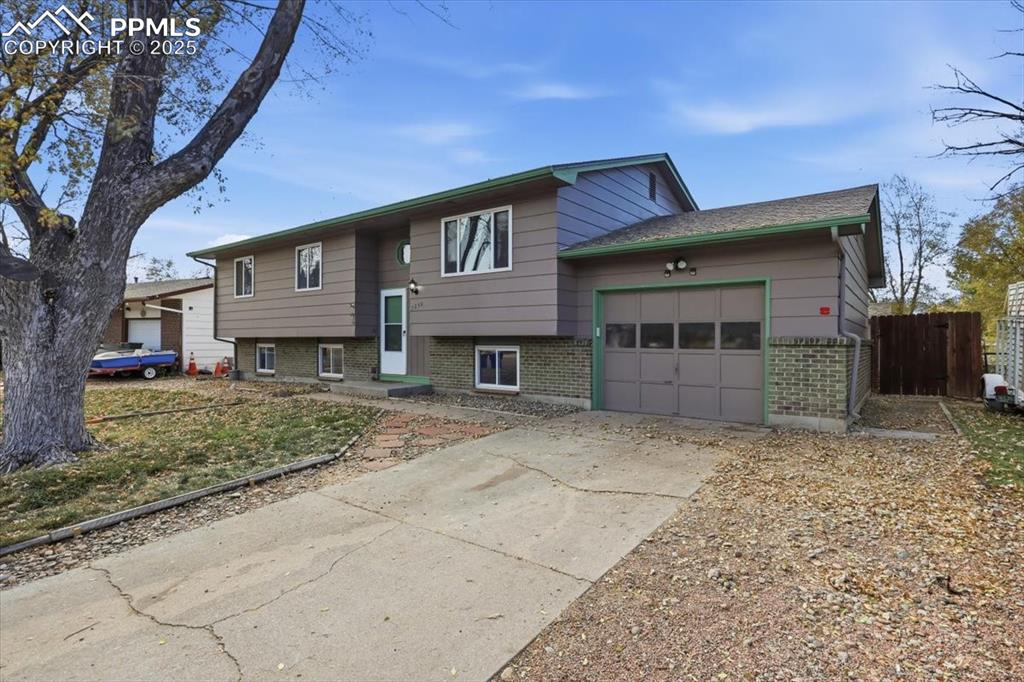 Image 21 of 26: Bi-level home featuring an attached garage, brick siding, and concrete driv