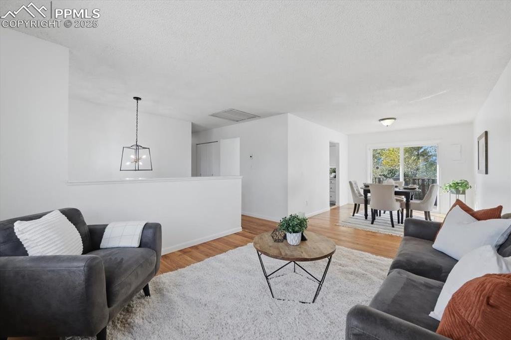 Image 4 of 26: Living area featuring wood finished floors and a chandelier