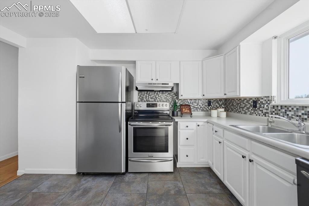 Image 6 of 26: Kitchen with appliances with stainless steel finishes, light countertops, w