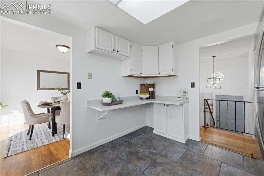 Image 7 of 26: Kitchen featuring white cabinetry, light countertops, a chandelier, freesta