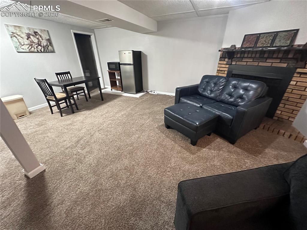 Image 2 of 44: This versatile living area features plush carpeting, a brick fireplace, and