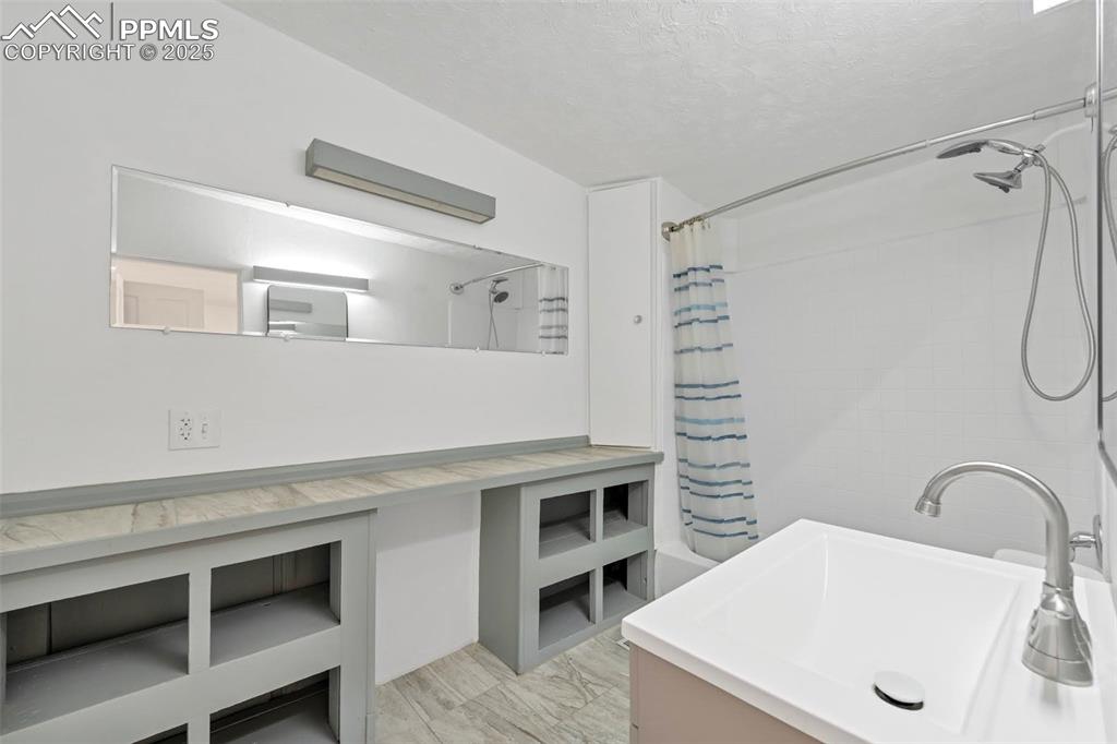 Image 18 of 34: Full Bathroom with built-in shelving and fresh updated look