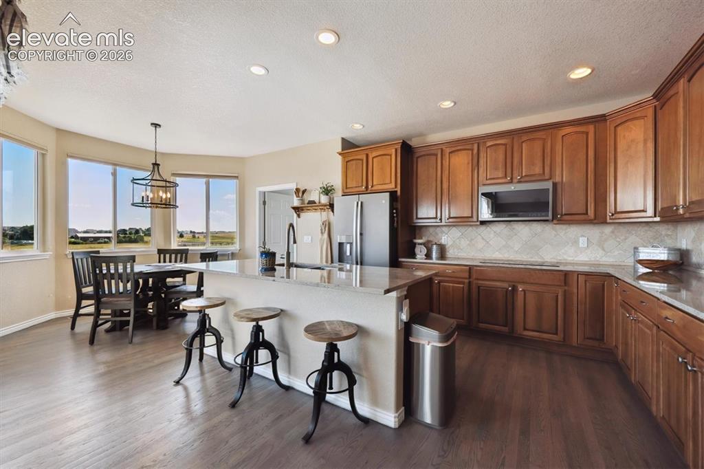 Image 11 of 46: Open-concept kitchen and dining area featuring wood-finish flooring, recess