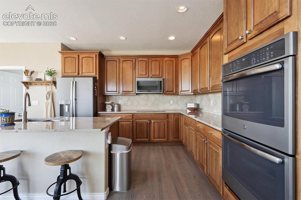 Image 12 of 46: Kitchen featuring wood cabinetry, stainless steel double wall ovens, wood-f