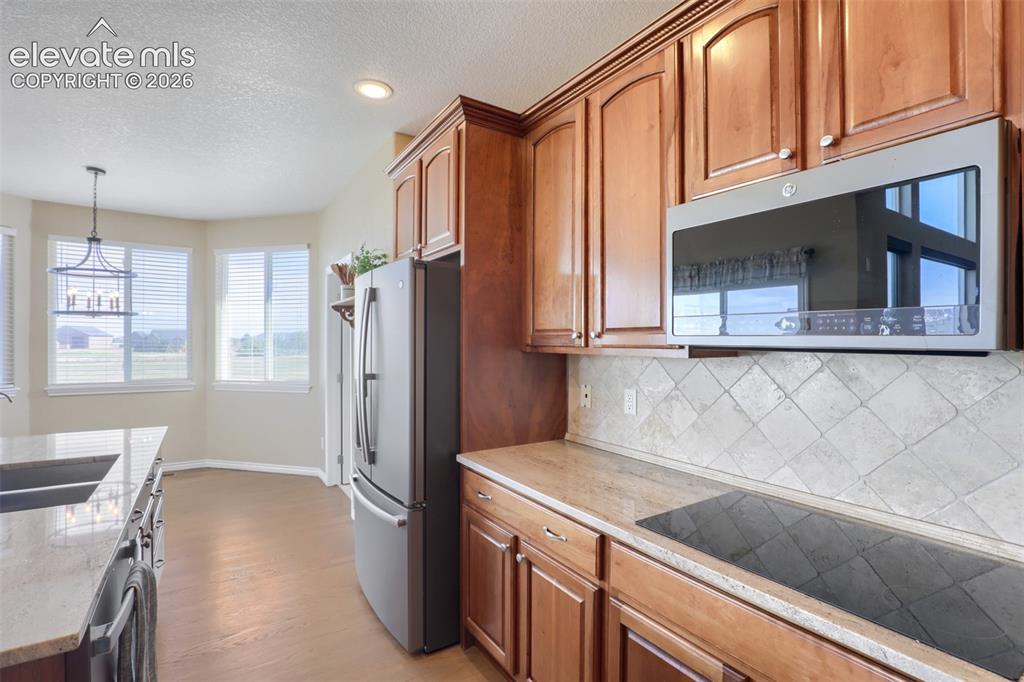 Image 13 of 37: Well-appointed kitchen showcasing a sleek induction glass cooktop, granite