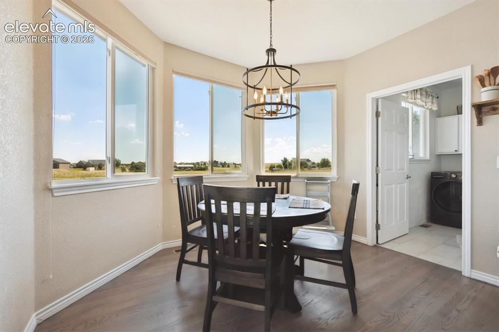 Image 15 of 46: Bright dining area featuring wood-finish flooring, a contemporary chandelie