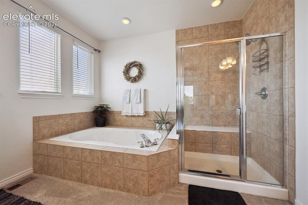 Image 20 of 46: Soaking tub with tile surround, separate enclosed shower, and dual windows