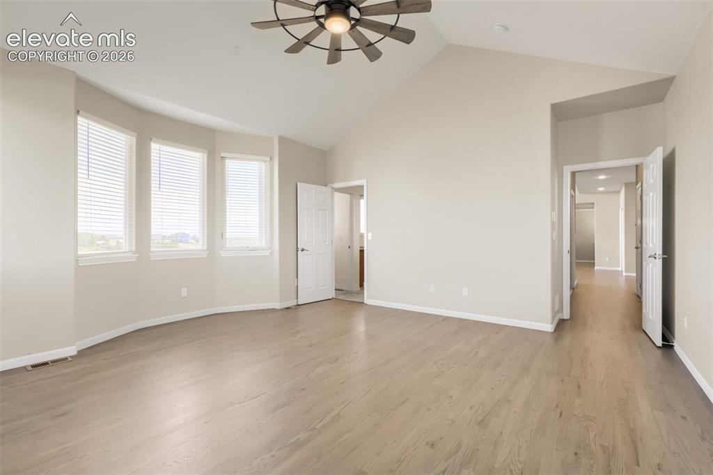 Image 20 of 37: Spacious and serene main floor primary suite featuring dramatic vaulted cei