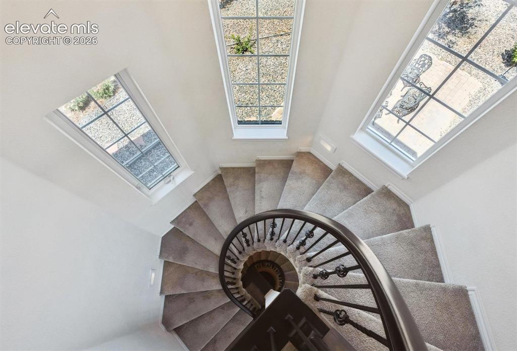 Image 21 of 46: Curved staircase featuring carpeted treads and a wrought iron banister, com