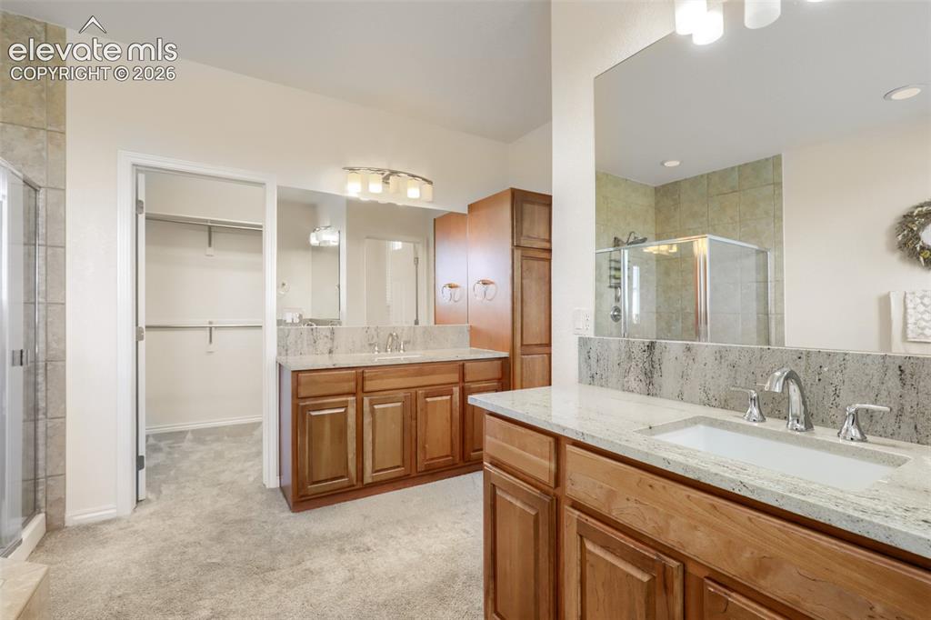 Image 21 of 37: Luxuriously appointed primary bath featuring dual split vanities with warm