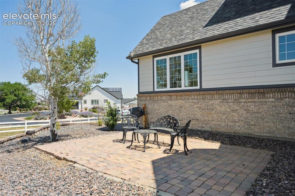 Image 33 of 46: Exterior featuring a stone paver patio, brick and siding facade, and a whit