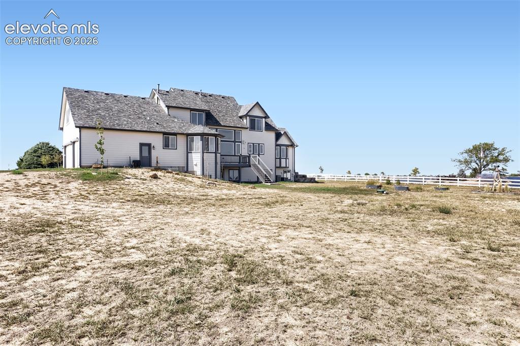 Image 33 of 37: Multi-story exterior with a shingle roof, multiple windows, and an upper-le