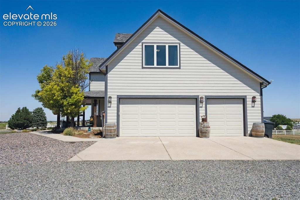 Image 40 of 46: Two-car garage with panel doors, sconce lighting, and a windowed gable end