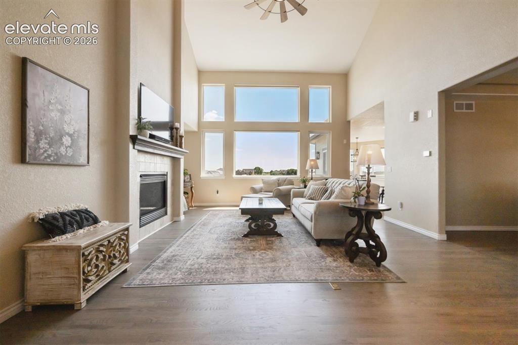 Image 5 of 46: Living area featuring high vaulted ceilings, multiple large windows, wood-f