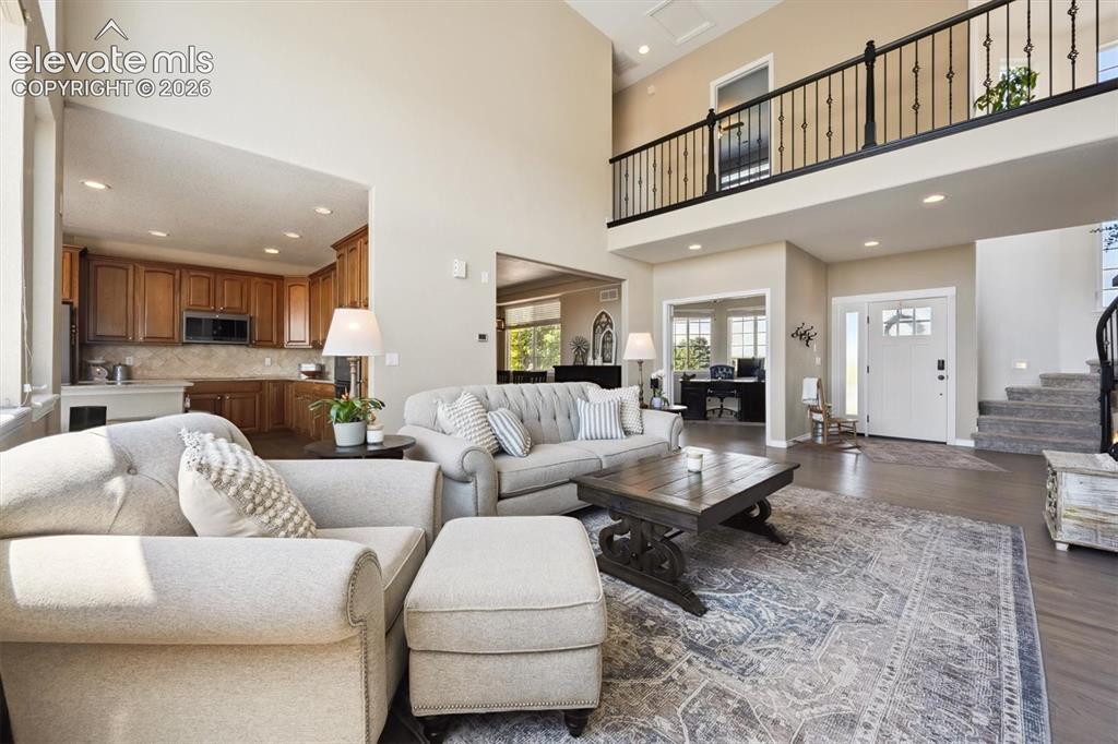 Image 7 of 46: Spacious living area featuring a two-story ceiling, a second-story balcony
