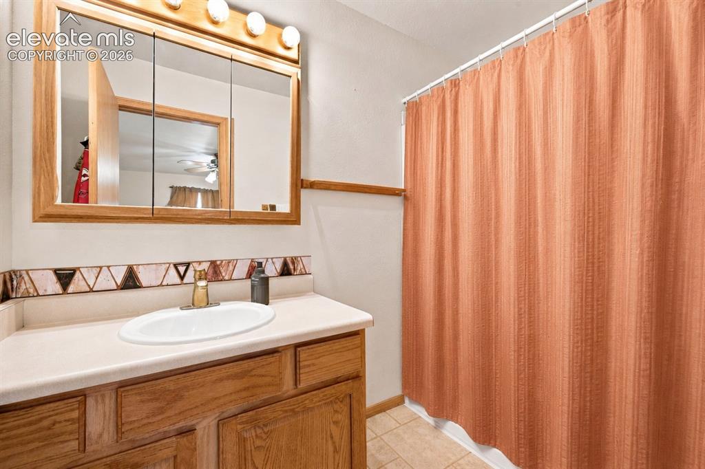 Image 12 of 37: Wood-finish vanity with a light-toned countertop, oval undermount sink, and