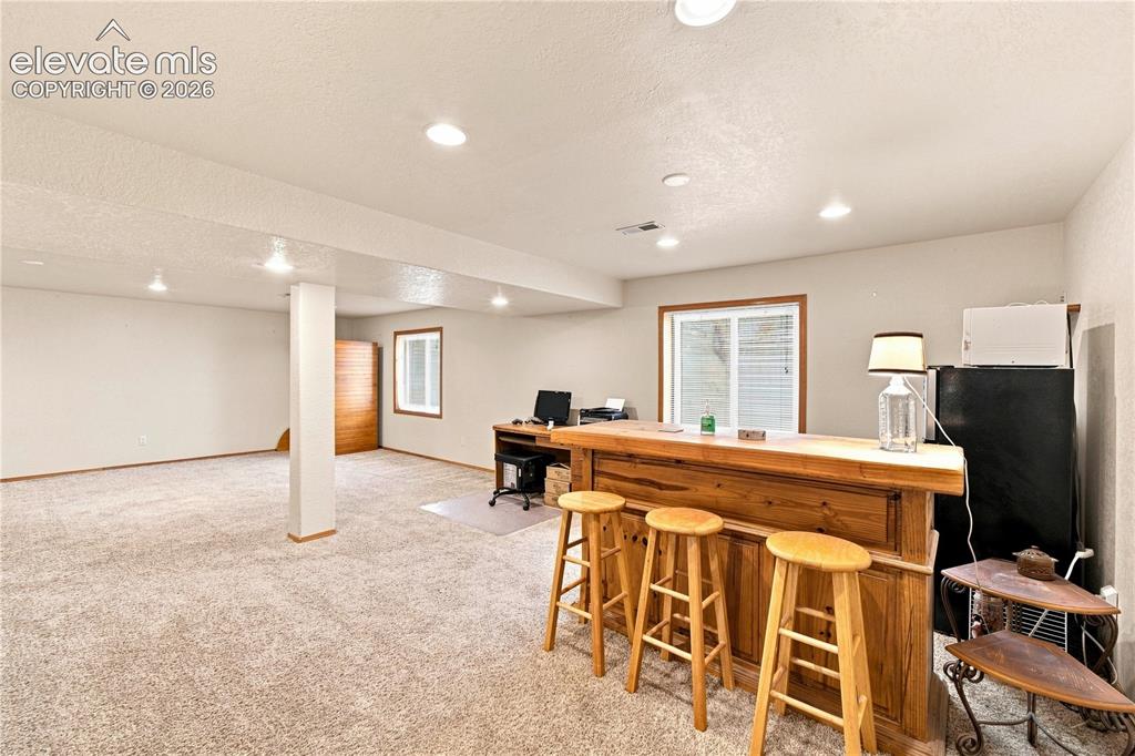 Image 16 of 37: Open lower level featuring recessed lighting, a wooden built-in bar, and ne