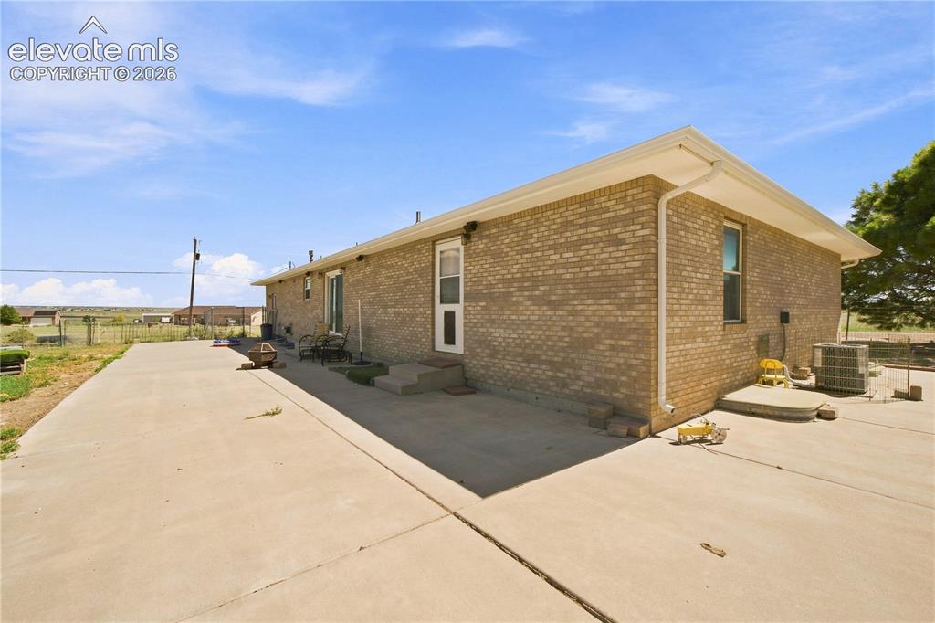 Image 25 of 37: Brick exterior with a large concrete driveway and a concrete patio