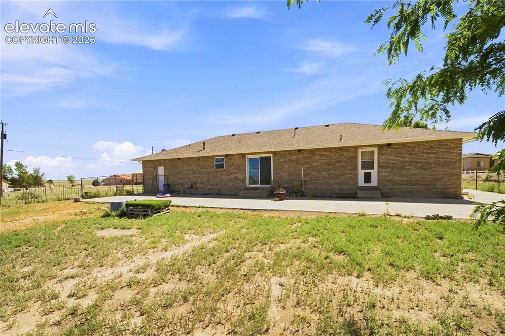 Image 26 of 37: Brick exterior with a shingle roof, sliding glass patio door, and concrete