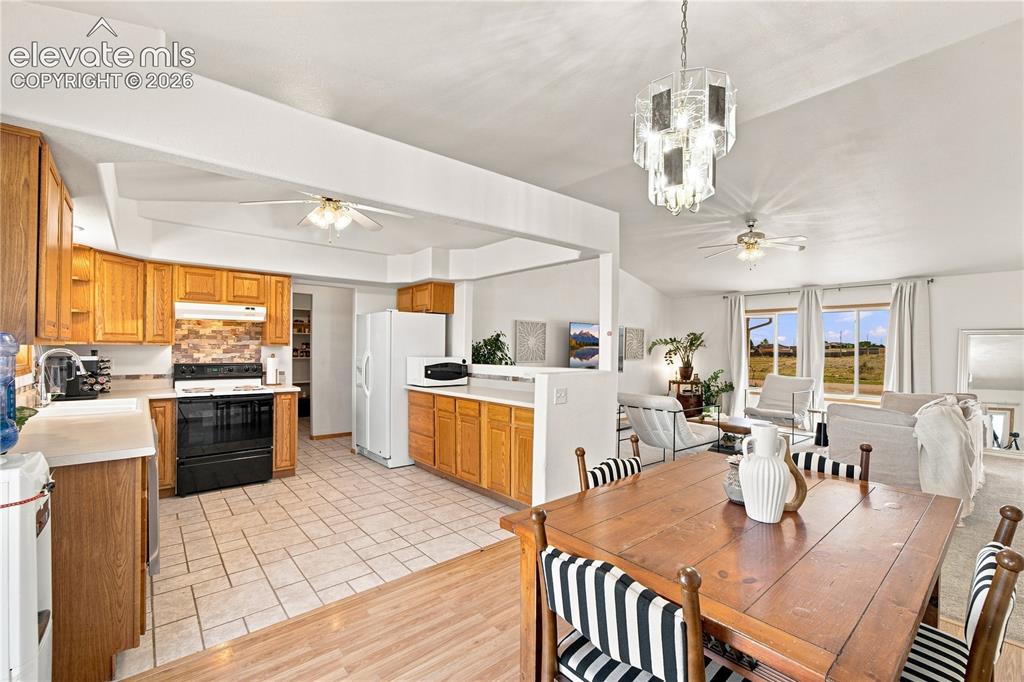 Image 6 of 37: Open-concept kitchen and dining area featuring wood cabinetry, tile floorin