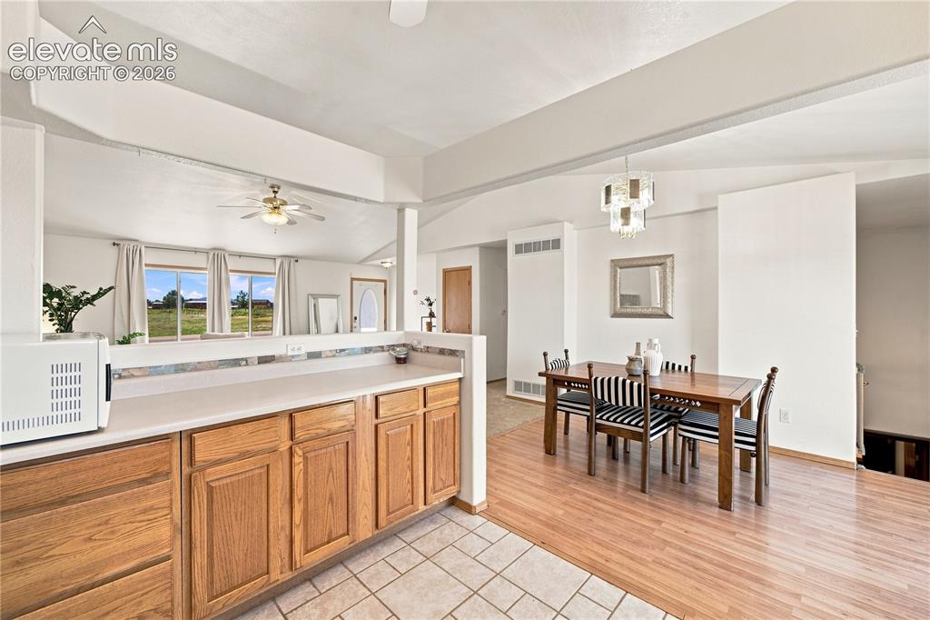 Image 7 of 37: Kitchen featuring wood-finish cabinetry, light-toned countertops, and tile