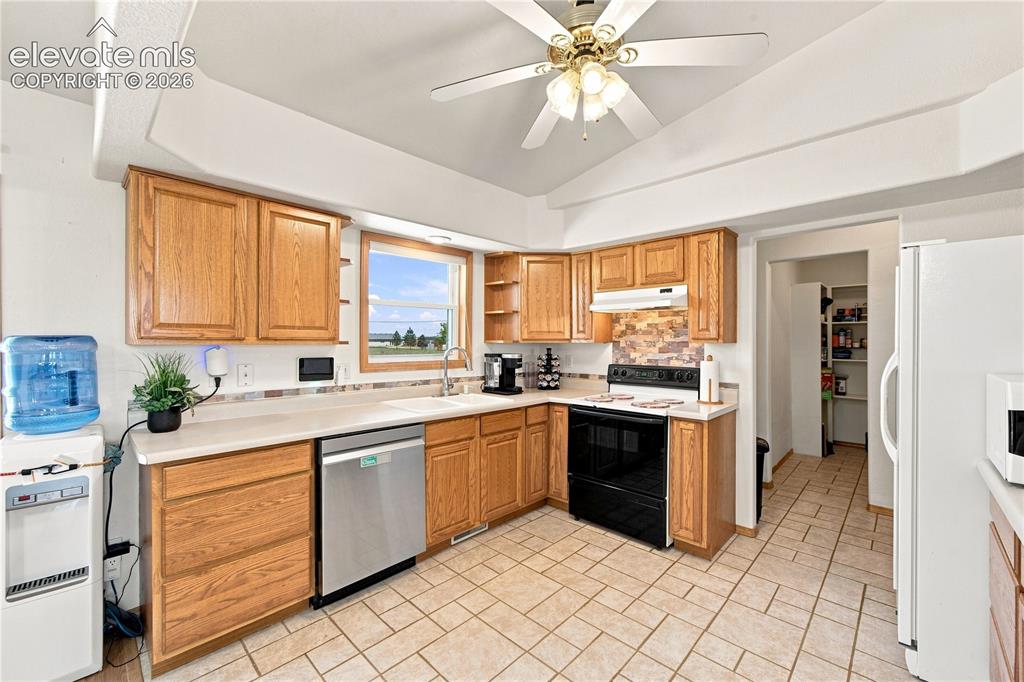 Image 8 of 37: Kitchen featuring wood cabinetry, light-toned countertops, tile flooring, a