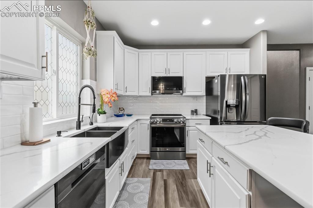 Image 13 of 43: Modern kitchen featuring white cabinetry, quartz countertops, a double basi
