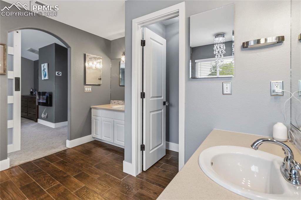 Image 25 of 43: Bathroom featuring a vanity with a white basin and chrome faucet, and wood-