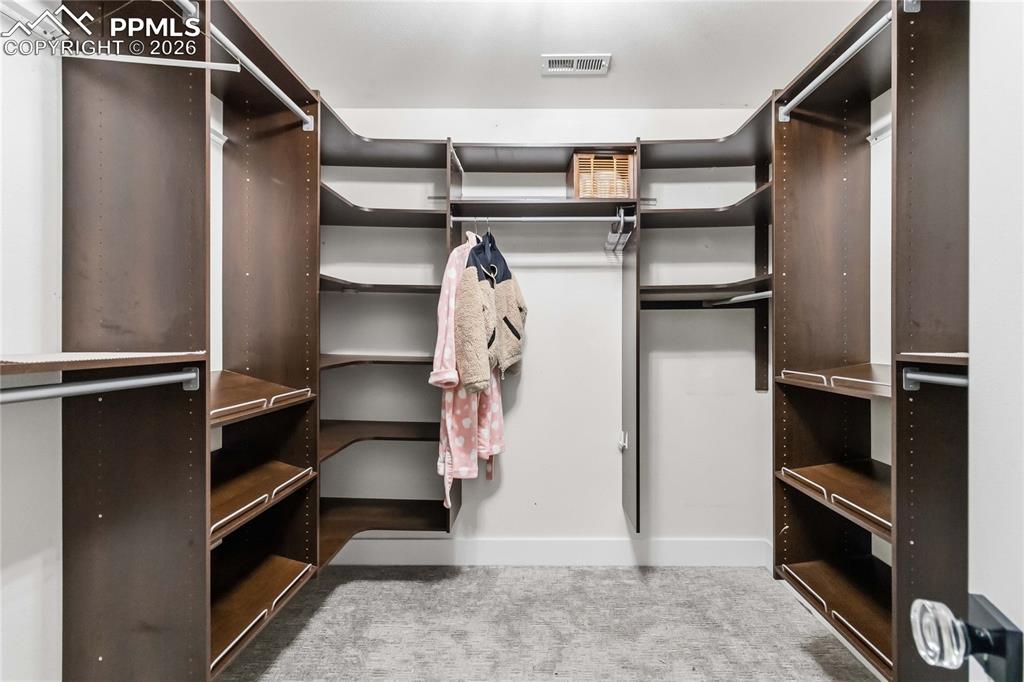 Image 26 of 43: Walk-in closet featuring extensive built-in shelving and hanging rods