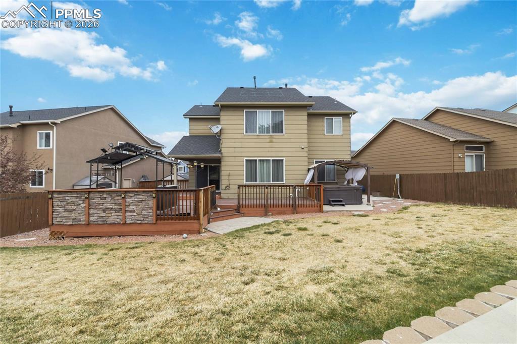 Image 40 of 43: The property features a spacious backyard with a deck, hot tub, 3 sheds and