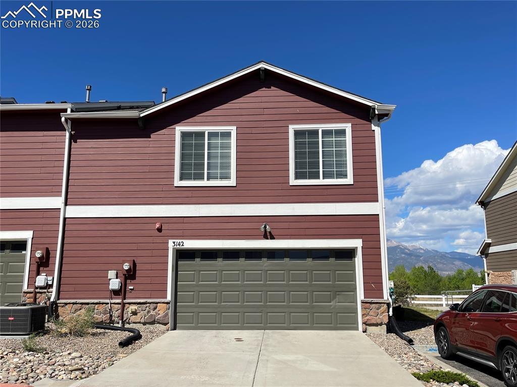 Image 1 of 15: Two-story townhome featuring maroon siding with white trim, a stone-accente